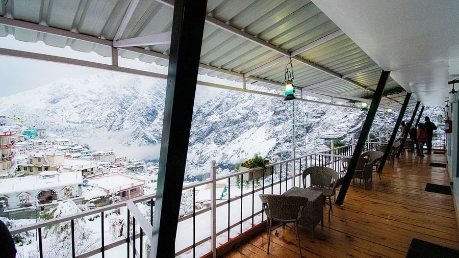 image of the balcony with wooden flooring overlooking the city views covered with white snow all around