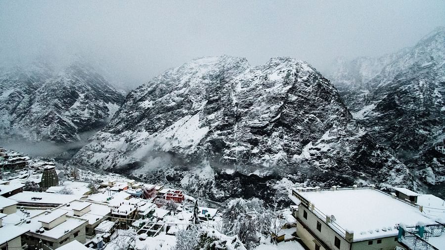 image of the mountain peaks covered with snow and mist  with small houses in the foothills