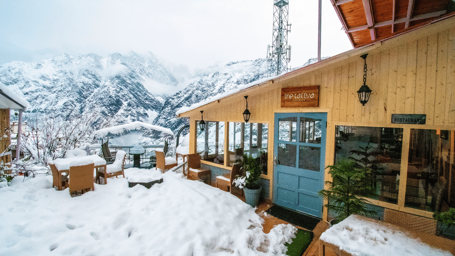 Facade of The Tattva, Joshimath, featuring the outdoor dining area with a thick blanket of snow covering the area.