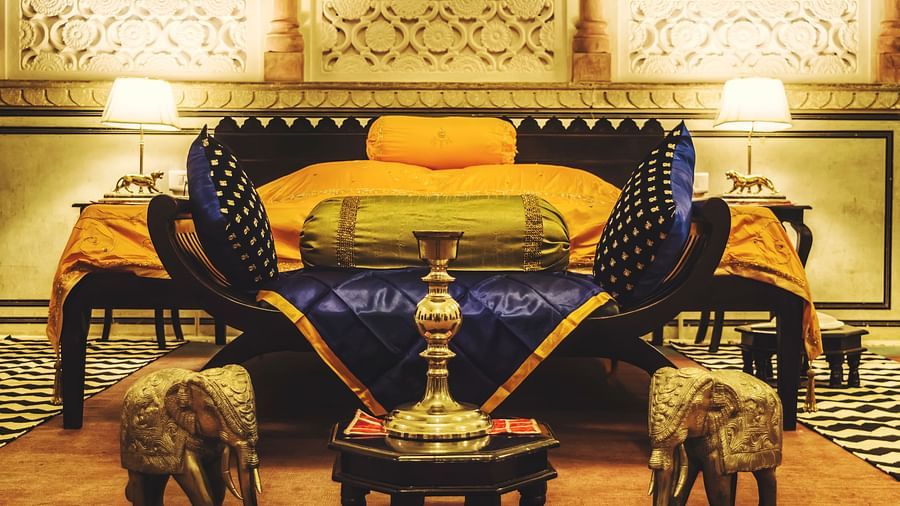 A luxuriously decorated bed at Umaid Vilas Jaipur with ornate elephant sculptures at its foot, showcasing traditional Indian design.
