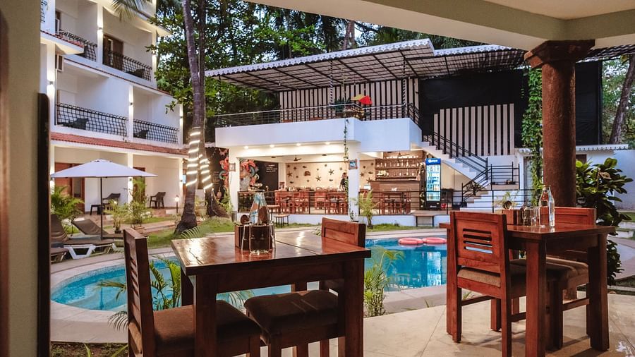 Outdoor dining area overlooking the swimming pool with wooden tables and chairs at The Verda de Miranda Resort.