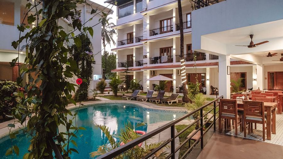 Poolside view with dining arrangements and rooms with balconies in the background at The Verda de Miranda Resort.