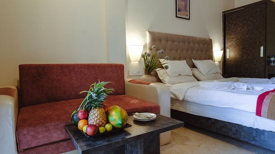 A cosy bedroom with a bed, a red sofa, and a fresh fruit platter on the table – The Verda de Miranda Resort.