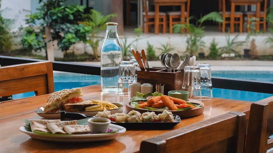 Outdoor dining setup with a variety of dishes beside a pool at The Verda de Miranda Resort.