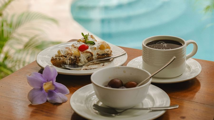 Breakfast spread with coffee, juice, and dessert beside a swimming pool at The Verda de Miranda Resort.