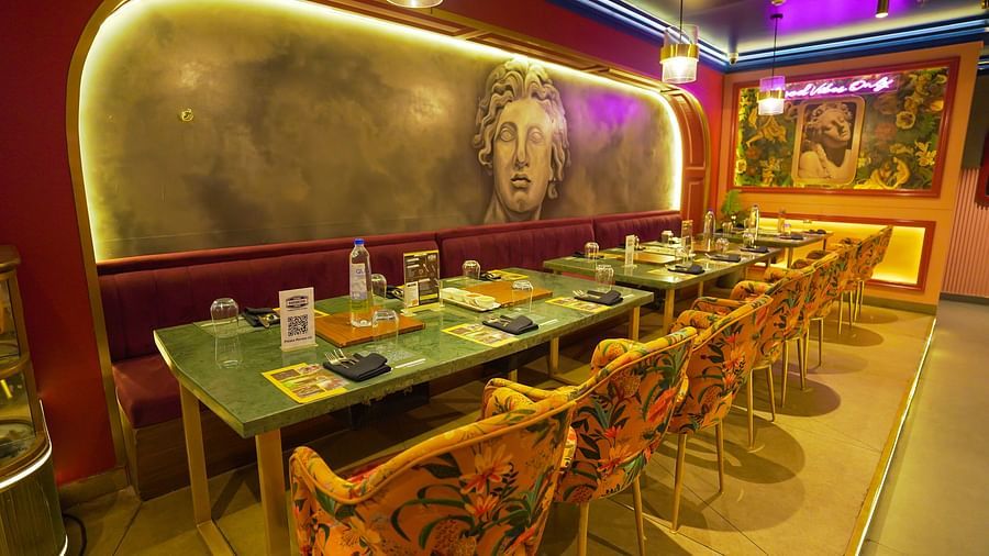 A shot of tables at the restaurant with a portrait of a greek sculpture behind Themis Barbecue House NSP Pitampura