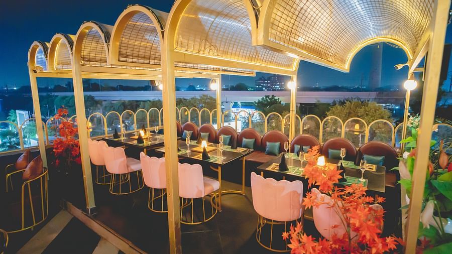 An image of a rooftop restaurant featuring chairs and tables set at Themis Barbecue House, NSP Pitampura