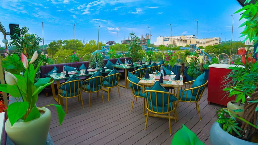 An image of a restaurant in a rooftop surrounded by plants at Themis Barbecue House, NSP Pitampura