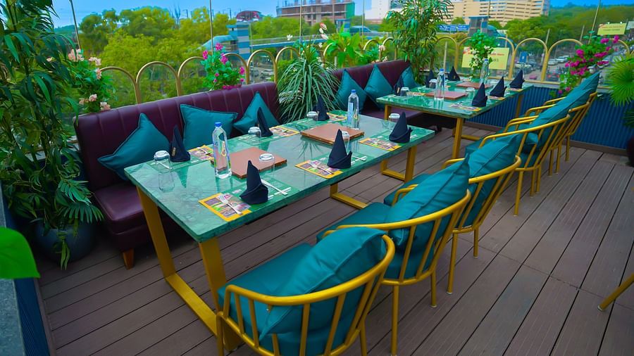 An image of a restaurant at a rooftop surrounded by plants at Themis Barbecue House, NSP Pitampura
