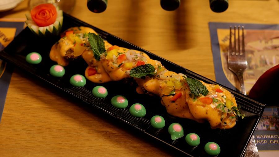 An image of a platter where grilled food items are placed and garnished with mayo and basil leaves at Themis Barbecue House, NSP Pitampura