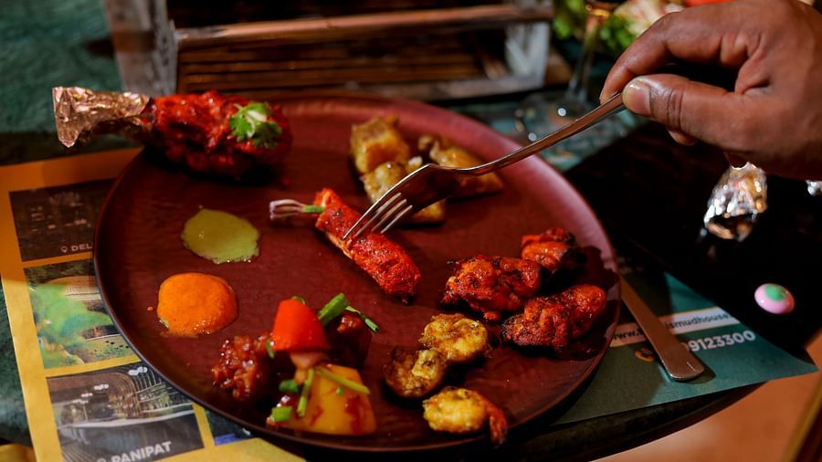 An image of a person having grilled pieces of meat from his plate - Themis Barbecue House, NSP Pitampura