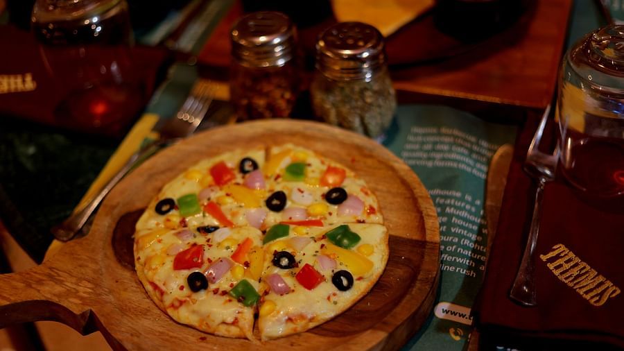 An image of pizza placed on a wooden serving tray - Themis Barbecue House, NSP Pitampura