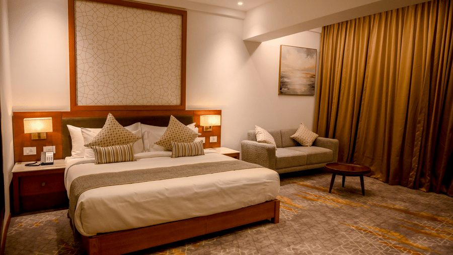 A hotel bedroom displaying a king size bed, carpeted flooring, and a small sofa setup near the window at Tiara by MPS.