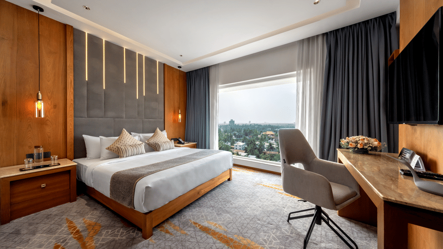 A bedroom space featuring a king size bed, wooden work desk, an office chair, and large window at Tiara by MPS.