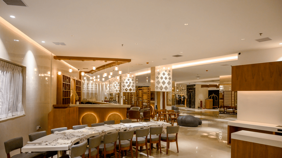 A large dining hall featuring table arrangement with chairs alongside separate seating options and a bar area at Tiara by MPS.