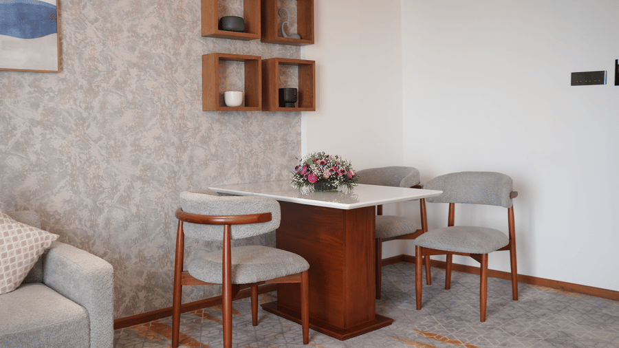 A dining table set with 3 chairs positioned next to a patterned feature wall at Tiara by MPS.