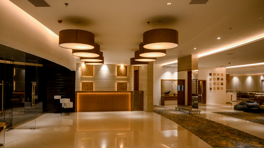 An expansive hotel reception area featuring a front desk under large cylindrical pendant lights at Tiara by MPS.