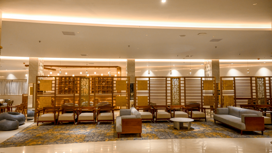 A wide seating area within a hotel lounge featuring multiple armchairs and sofas arranged along a patterned carpet runner at Tiara by MPS.