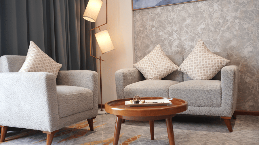 A seating corner featuring a 2 seater sofa, an armchair, a wooden coffee table, and a tall floor lamp at Tiara by MPS.