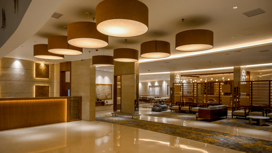 A large reception lobby displaying a front counter illuminated by large cylindrical hanging lamps over a polished floor at Tiara by MPS.