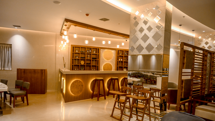 A comprehensive view of a restaurant interior showcasing a lit bar counter, various seating setups, and decorative partitions at Tiara by MPS.