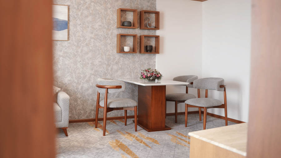 A dedicated dining corner inside a hotel suite featuring a table with chairs next to wall mounted display shelves at Tiara by MPS.