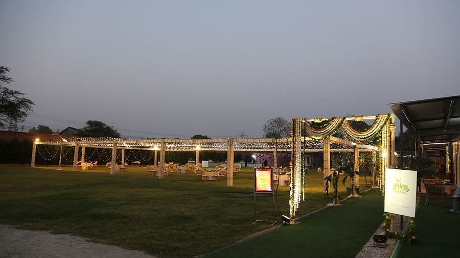 Lawn and entrance structure at Tisya Farms, Gurgaon during daylight with a green carpet and decorative signage