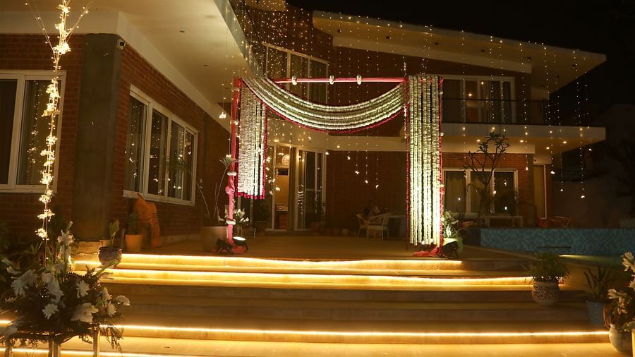 Main building entrance at Tisya Farms, Gurgaon decorated with lights and hanging fabric, captured at night.