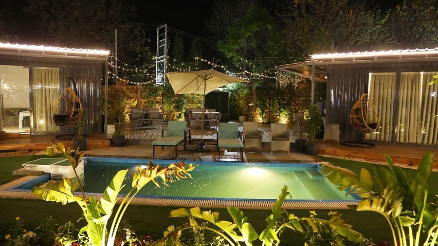 Night view of swimming pool with plants and lighting around the villa at Tisya Farms, Gurgaon.