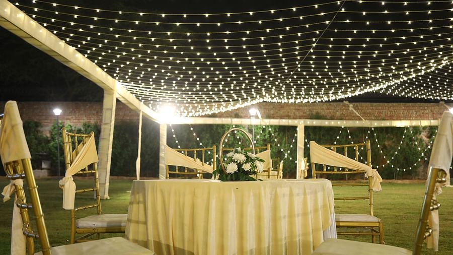 Outdoor table setup at Tisya Farms, Gurgaon under a canopy of hanging string lights.