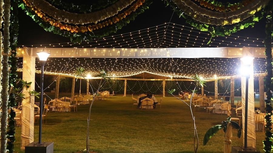 Lawn setup with chairs and lights under a canopy decorated with flowers at Tisya Farms, Gurgaon.