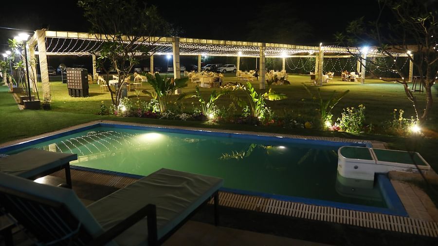 Poolside view illuminated with lights during nighttime at Tisya Farms, Gurgaon.