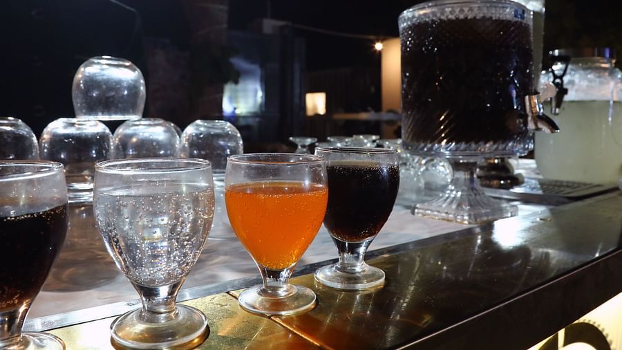 Beverage counter at Tisya Farms, Gurgaon displaying glasses filled with orange, red, and dark drinks.