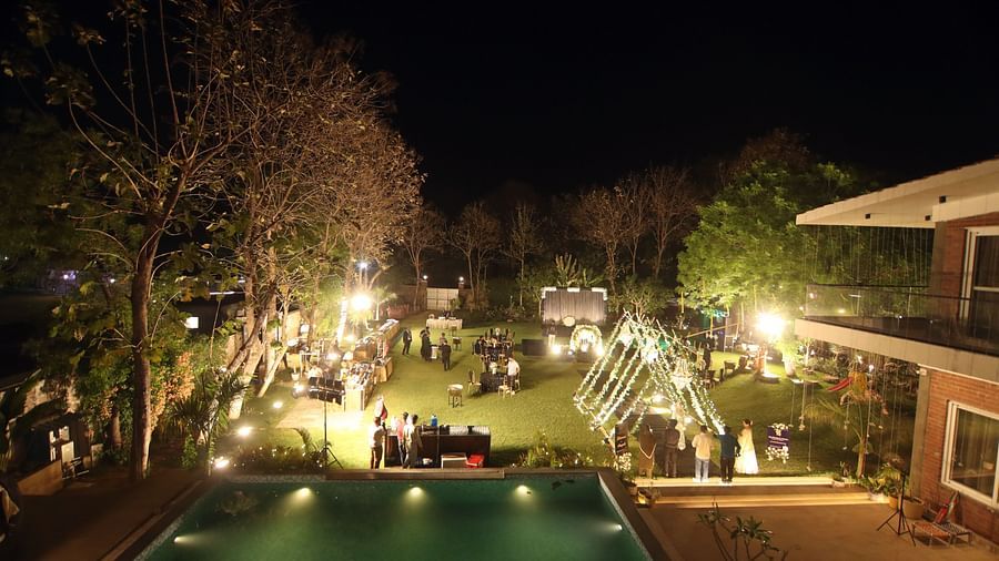 Elevated poolside view at night with event lighting and lawn setup at Tisya Farms, Gurgaon.