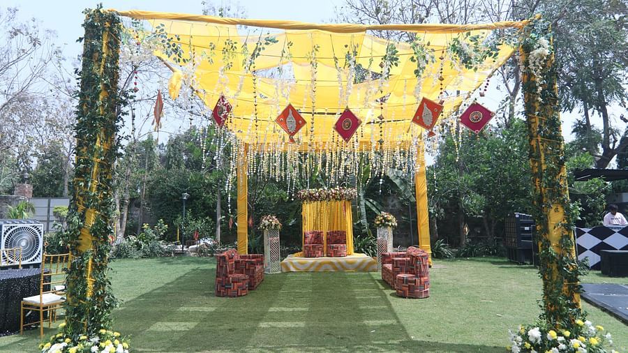 Daytime wedding setup with yellow drapes and floral arrangements at Tisya Farms, Gurgaon.