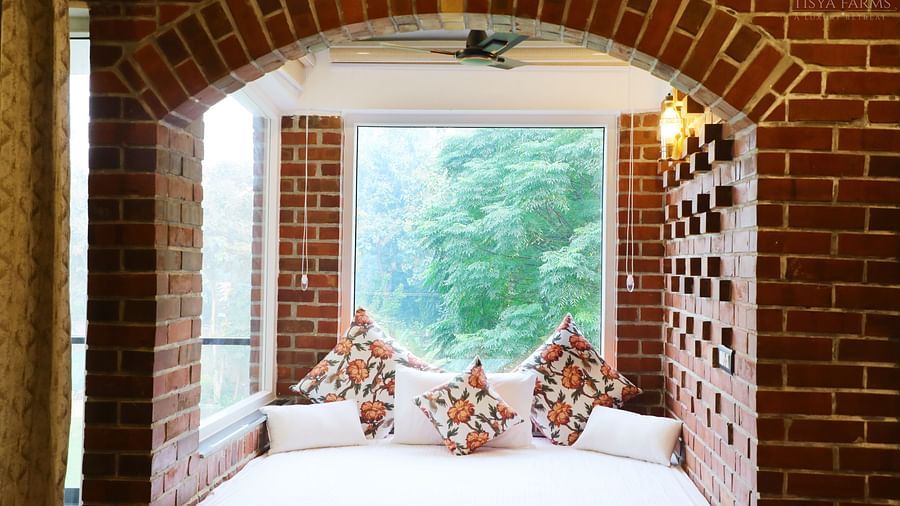 Niche bed space set into an arched brick alcove with pillows at Tisya Farms, Gurgaon.