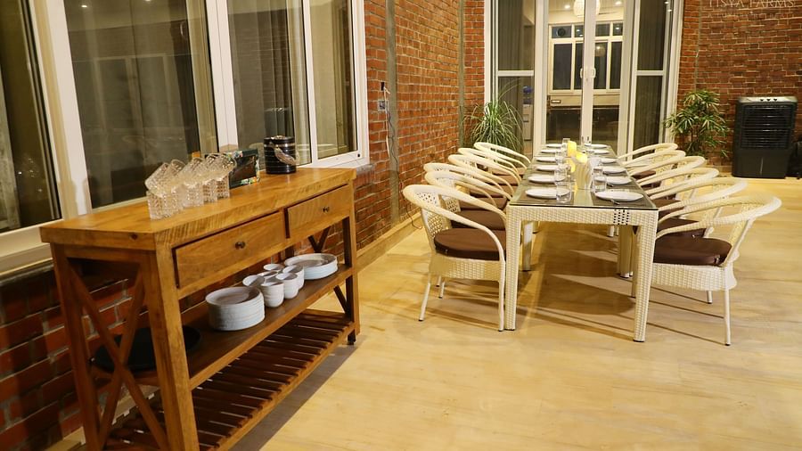 A dining table with cutlery and plates set for a meal at Tisya Farms, Gurgaon.