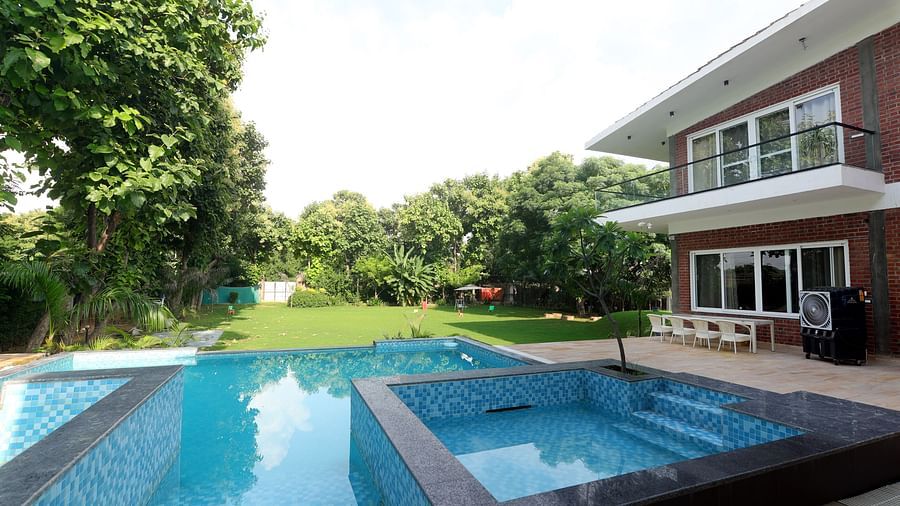 A  farmhouse with a sparkling swimming pool, surrounded by lush garden at Tisya Farms, Gurgaon.