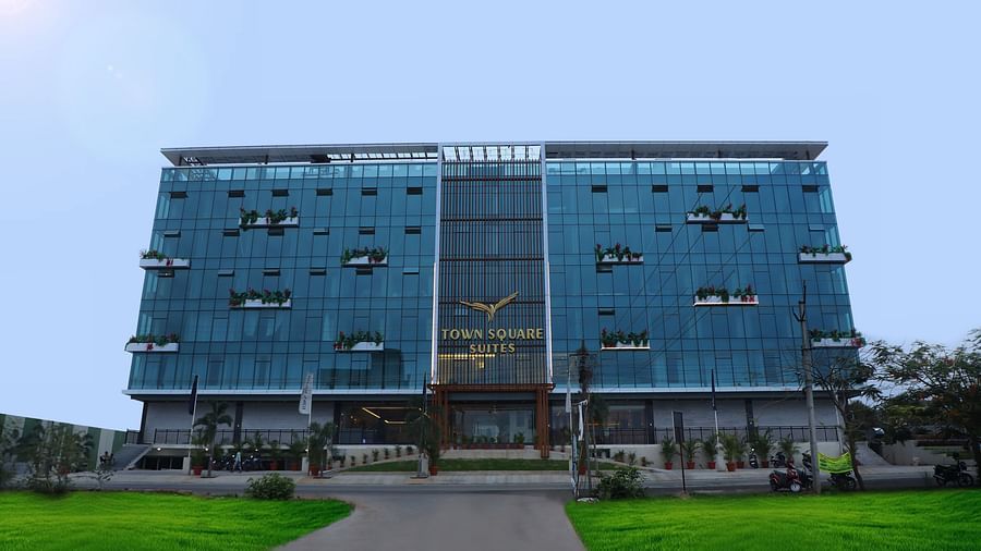 Exterior view of Town Square Suites showing modern architectural design and lush green lawn