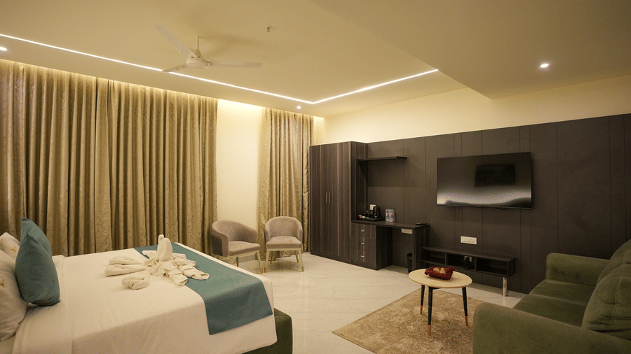 Premium room with double bed, wall-mounted TV and green sofa at Town Square Suites.