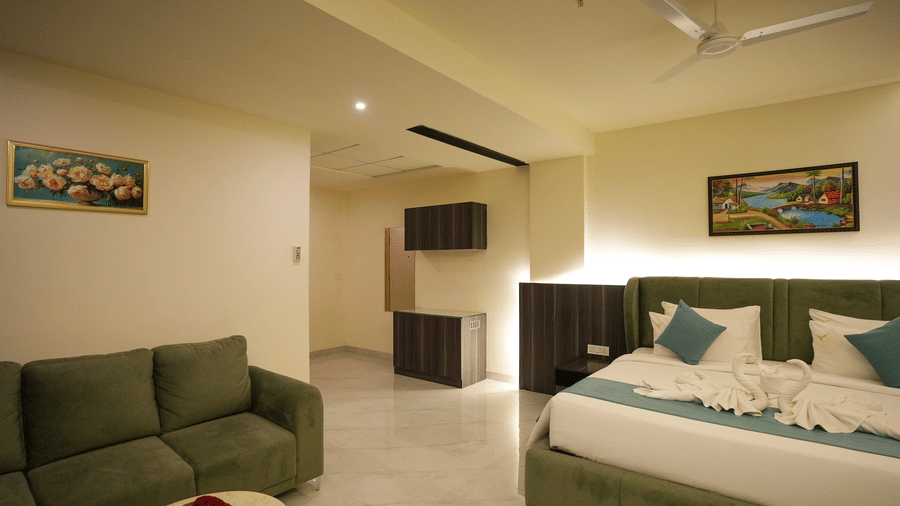 Skyline suite room with green sofa, single bed and cream interiors at Town Square Suites