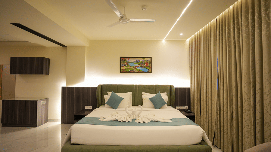 Skyline room with double bed, beige curtains and ceiling fan at Town Square Suites