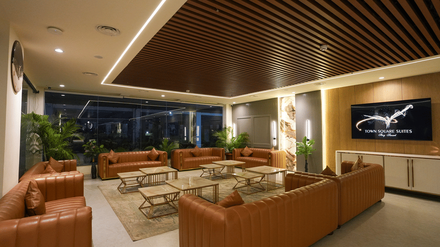 Cozy lounge seating at Town Square Suites with leather sofas, wood ceiling, and soft lighting.