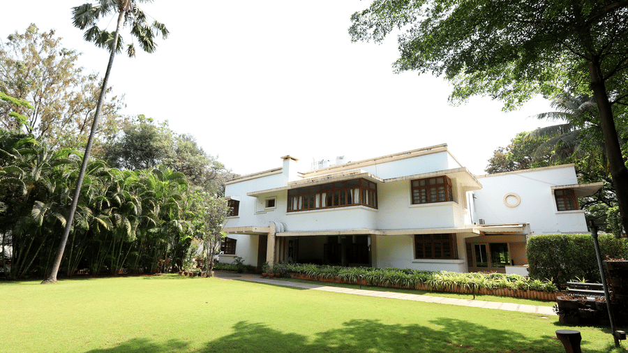A wide view of a manicured lawn at Trance Sunderban Resort leading to a colonial-style building under a clear sky.