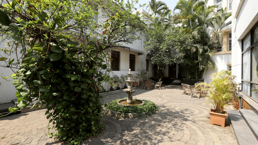 A courtyard at Trance Sunderban Resort with a small stone fountain, lush green climbing plants, and a paved circular floor.