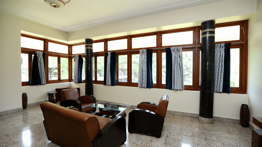 A private lounge space within the Osho Suite featuring leather armchairs, a glass coffee table, and large wooden-framed windows | Trance Sunderban Resort