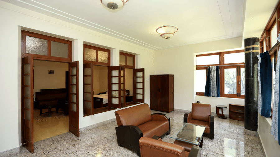 A private lounge space within the Osho Suite featuring leather armchairs, a glass coffee table, and large wooden-framed windows | Trance Sunderban Resort
