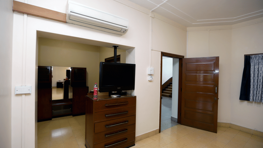 A view of the Osho Suite's entrance area featuring a dark wood dresser with a TV and a wardrobe nook | Trance Sunderban Resort