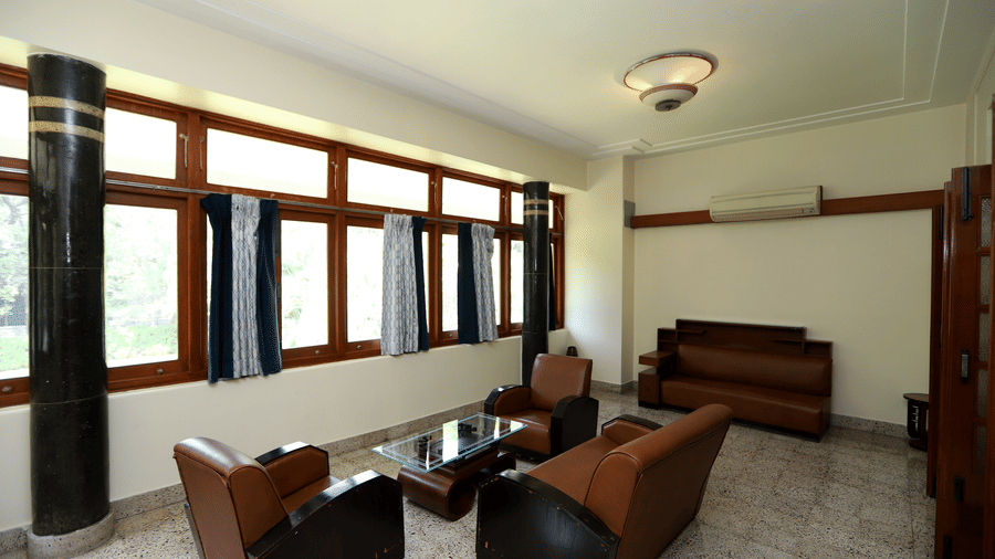 A private lounge space within the Osho Suite featuring leather armchairs, a glass coffee table, and large wooden-framed windows | Trance Sunderban Resort