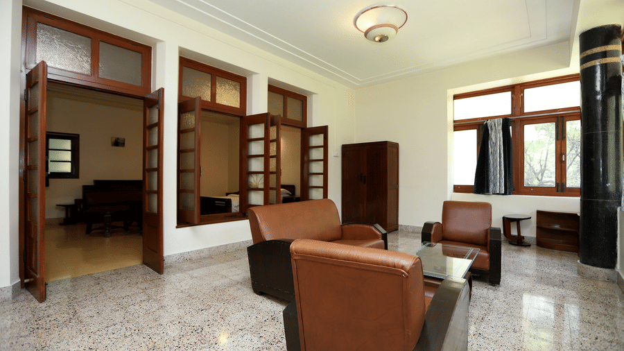 A private lounge space within the Osho Suite featuring leather armchairs, a glass coffee table, and large wooden-framed windows | Trance Sunderban Resort